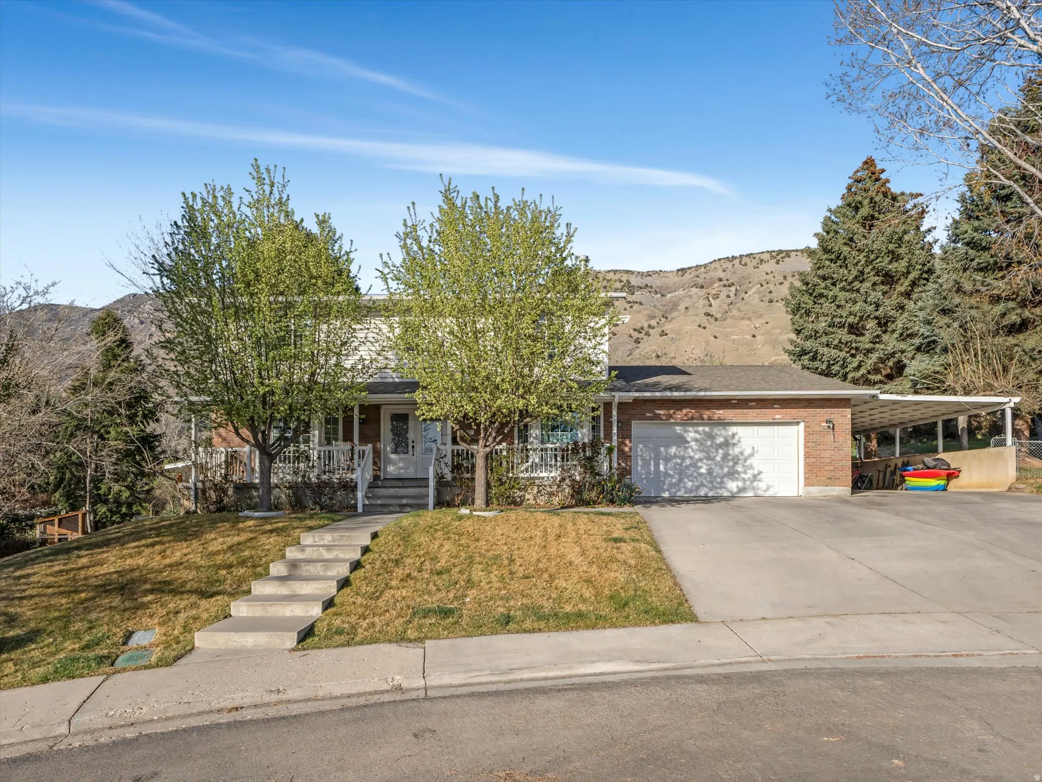 View of front of house featuring a mountain view, a garage, brick siding, concrete driveway, and a porch