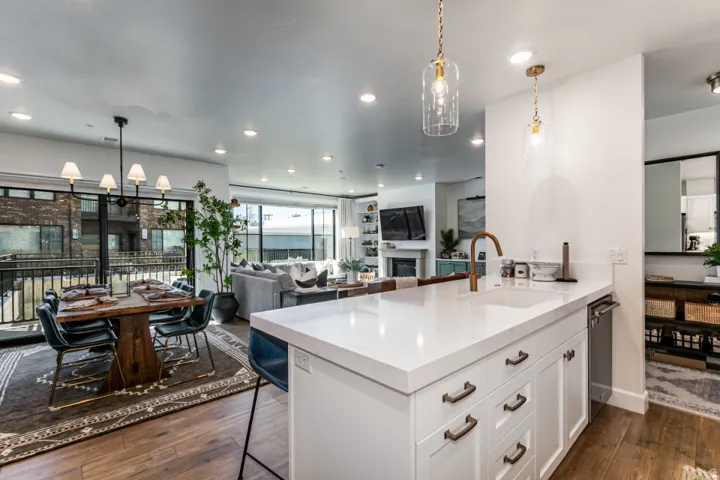 Kitchen featuring a breakfast bar, dark wood-style floors, a fireplace, a peninsula, and light stone countertops