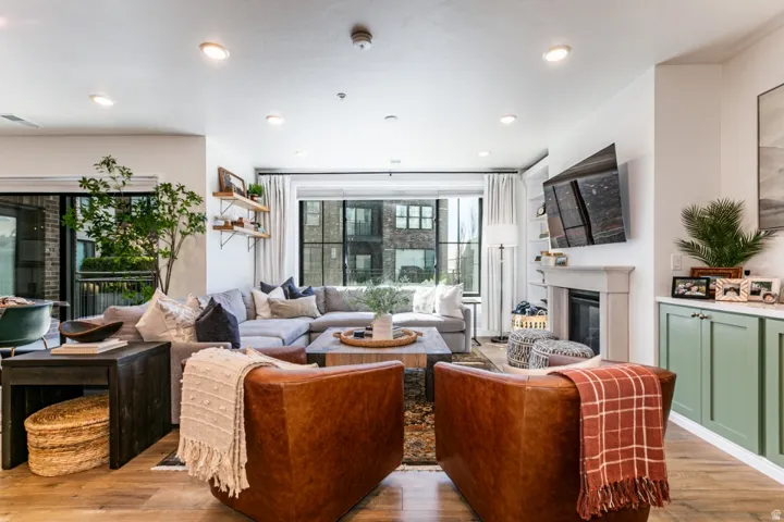 Living area featuring light wood-type flooring, a glass covered fireplace, and recessed lighting