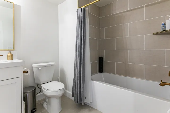 Full bathroom with vanity, light tile patterned floors, and shower / bath combination with curtain