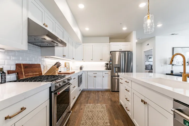 Kitchen featuring stainless steel appliances, white cabinets, and light stone counters