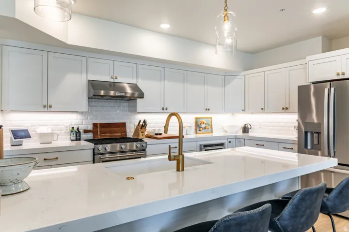 Kitchen with light stone countertops, white cabinetry, stainless steel appliances, and a kitchen bar