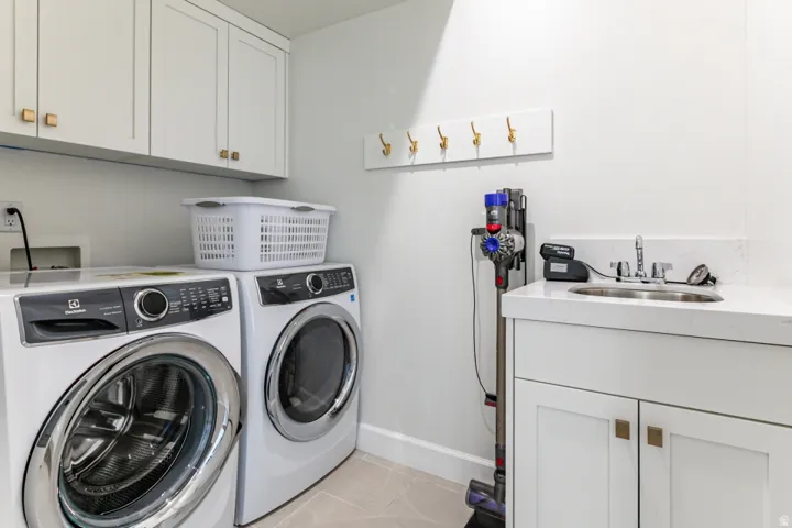 Laundry room with cabinet space, light tile patterned flooring, and independent washer and dryer