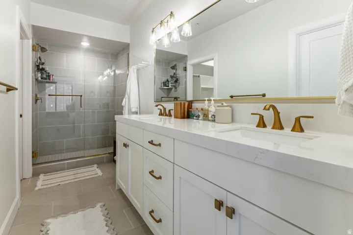 Bathroom with double vanity, a stall shower, and light tile patterned floors