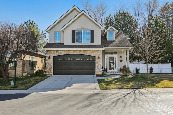Traditional home featuring concrete driveway, roof with shingles, stone siding, a garage, and stucco siding