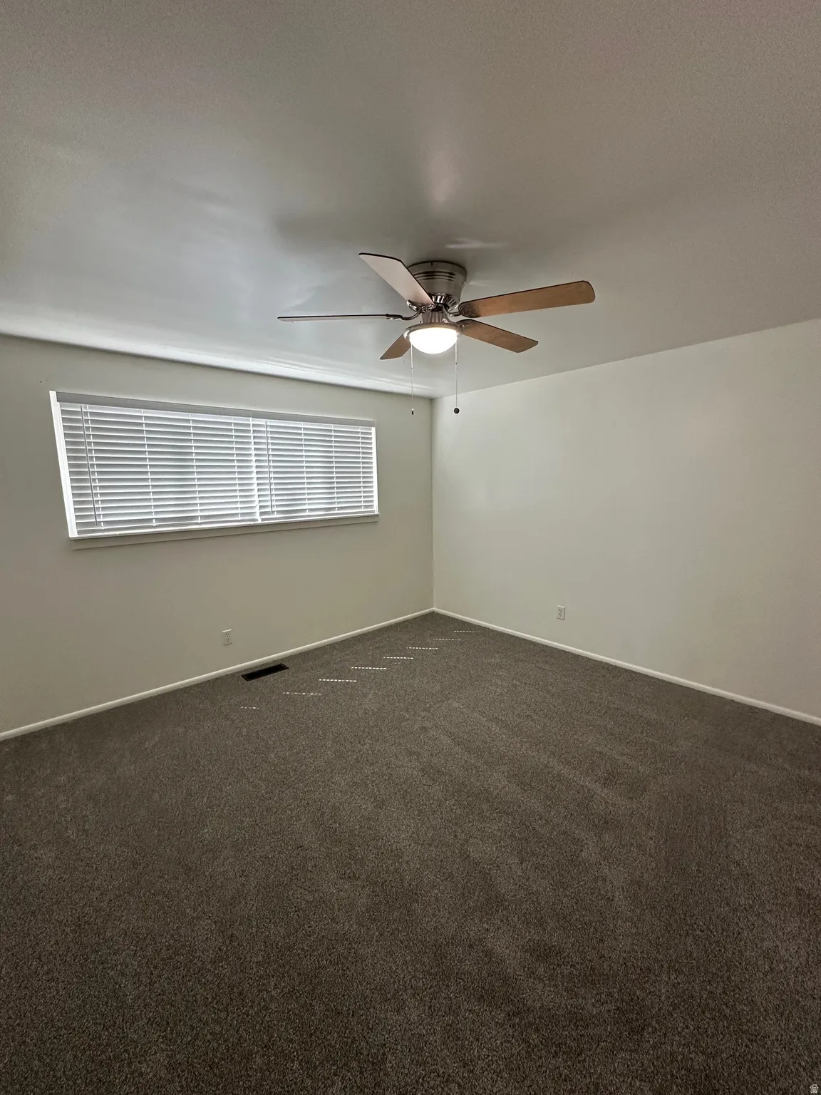 Spare room featuring dark carpet and a ceiling fan