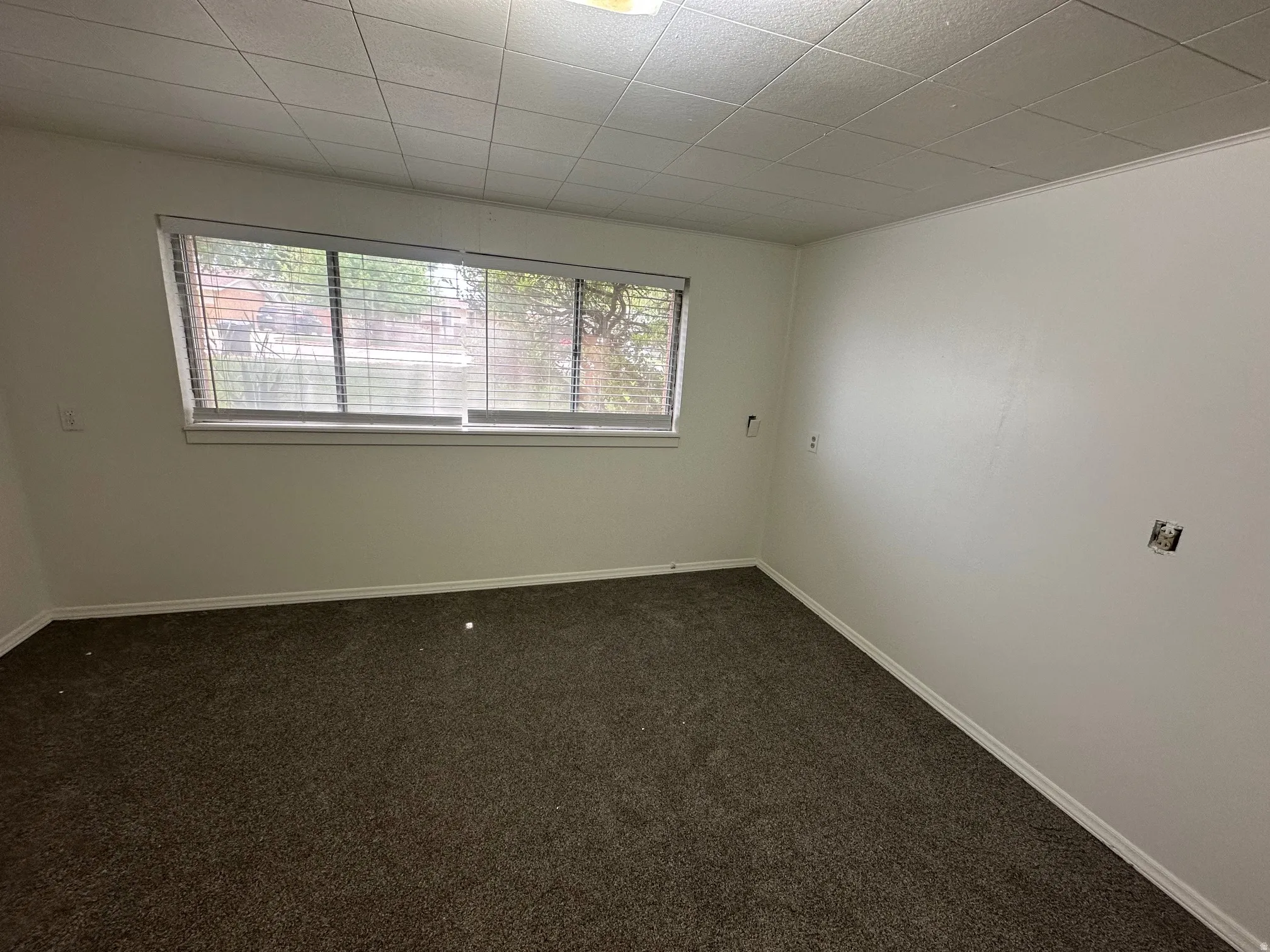 Empty room featuring dark colored carpet and baseboards