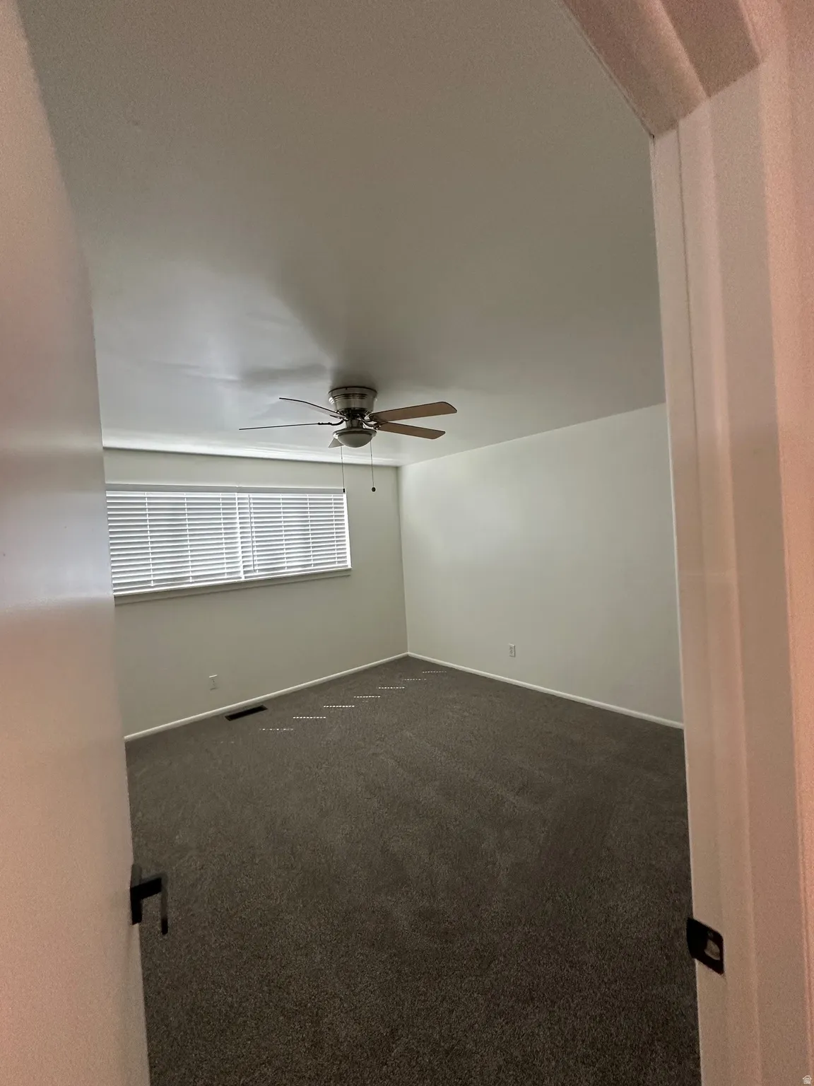 Empty room with dark carpet and ceiling fan