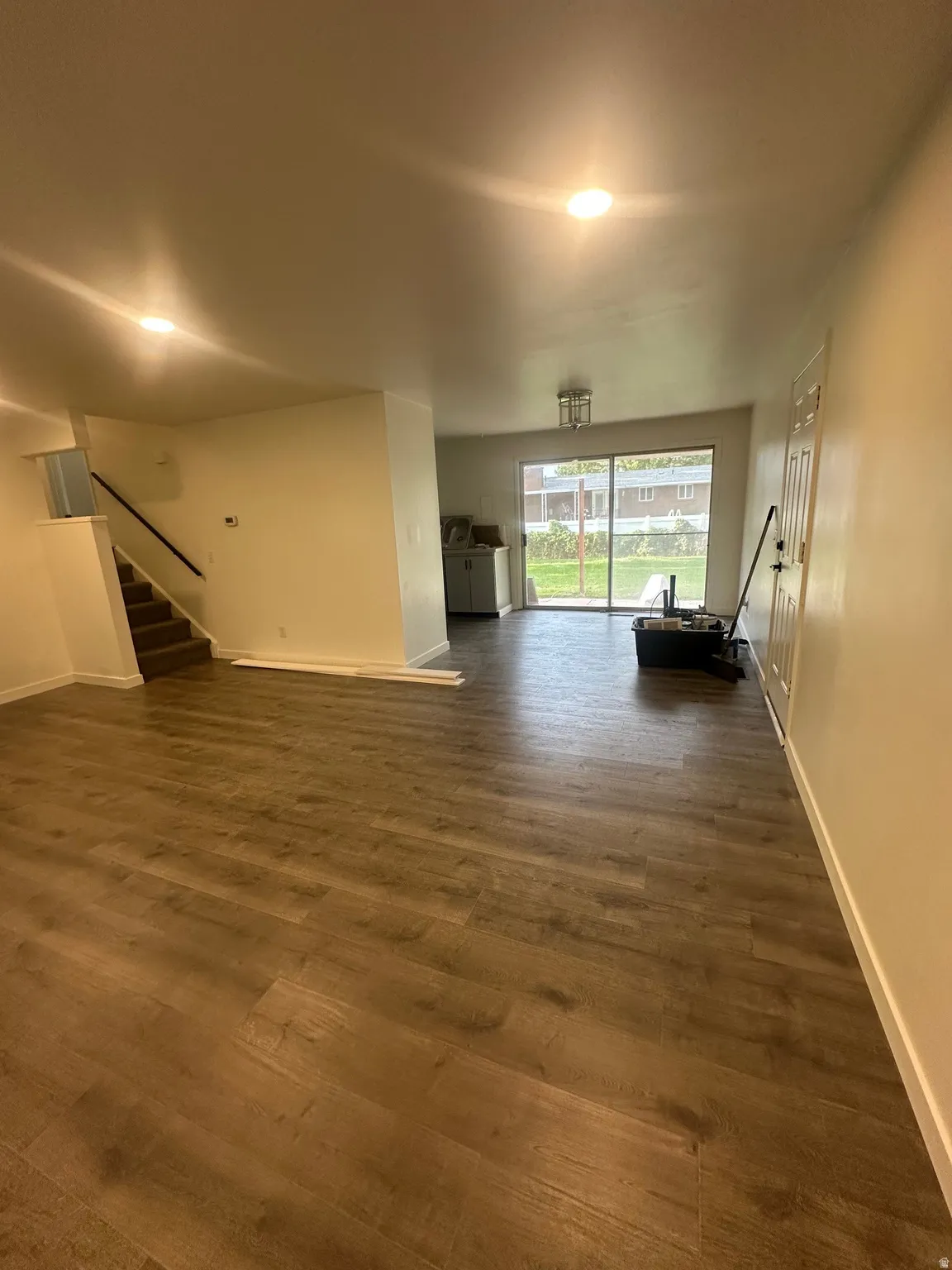 Unfurnished living room featuring stairs and dark wood finished floors