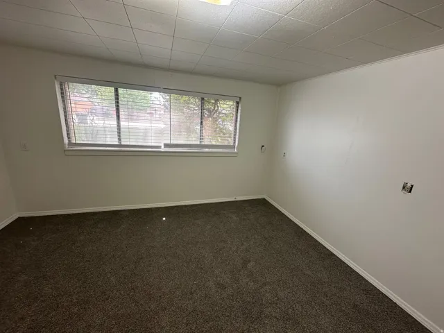 Empty room featuring dark colored carpet and baseboards