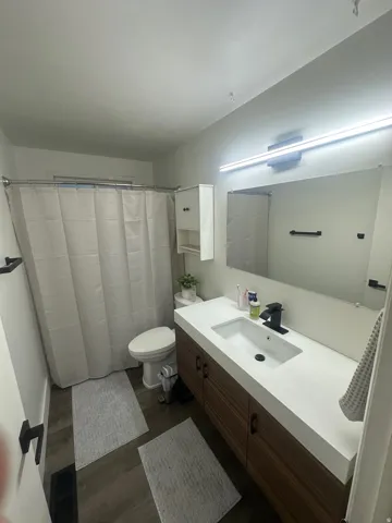 Full bathroom with vanity, a shower with shower curtain, and dark wood finished floors