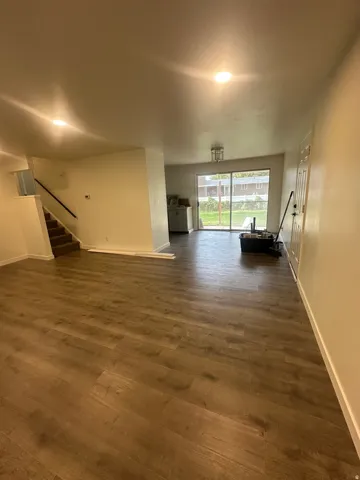 Unfurnished living room featuring stairs and dark wood finished floors