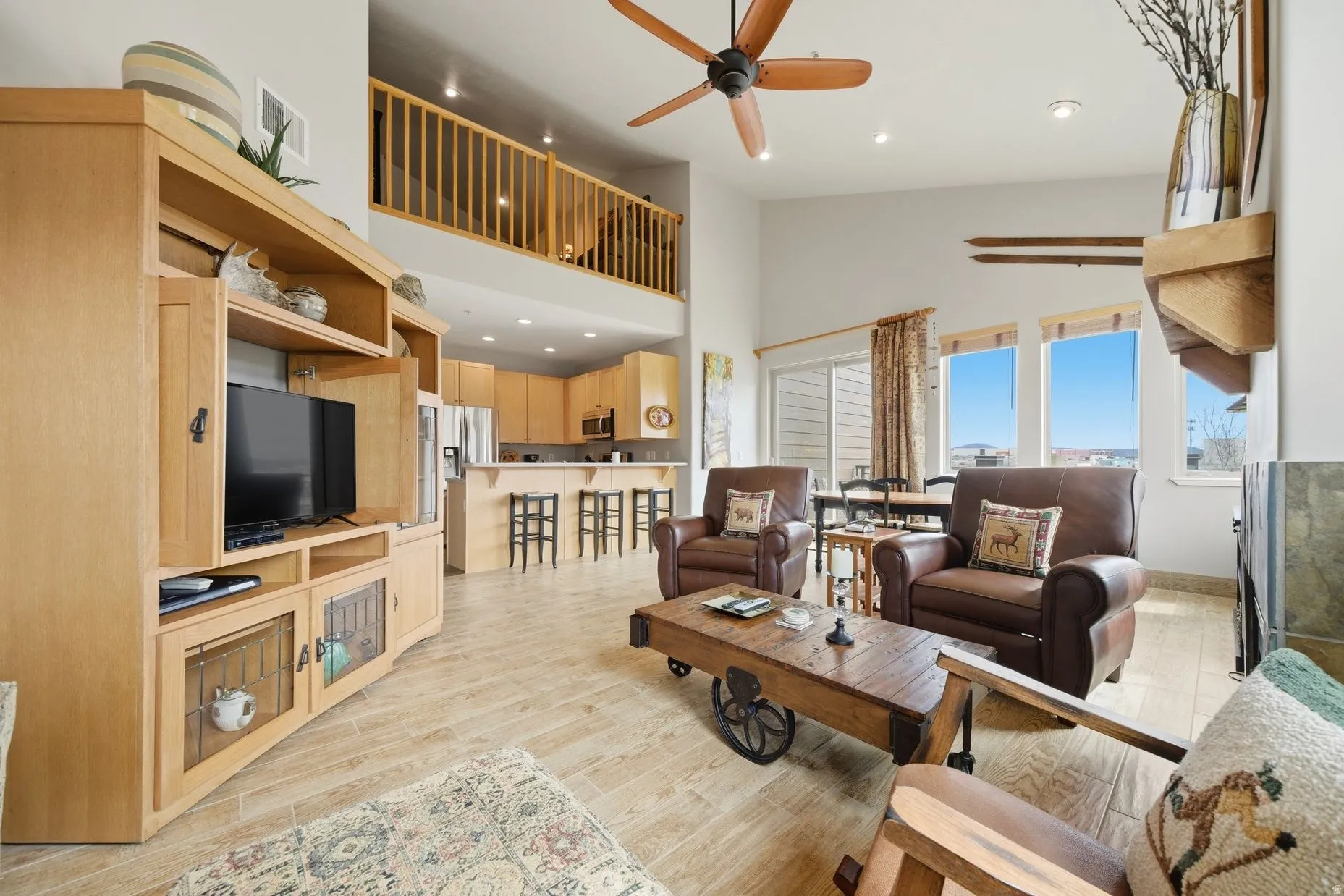 Living area with recessed lighting, a ceiling fan, a high ceiling, and light wood-style flooring