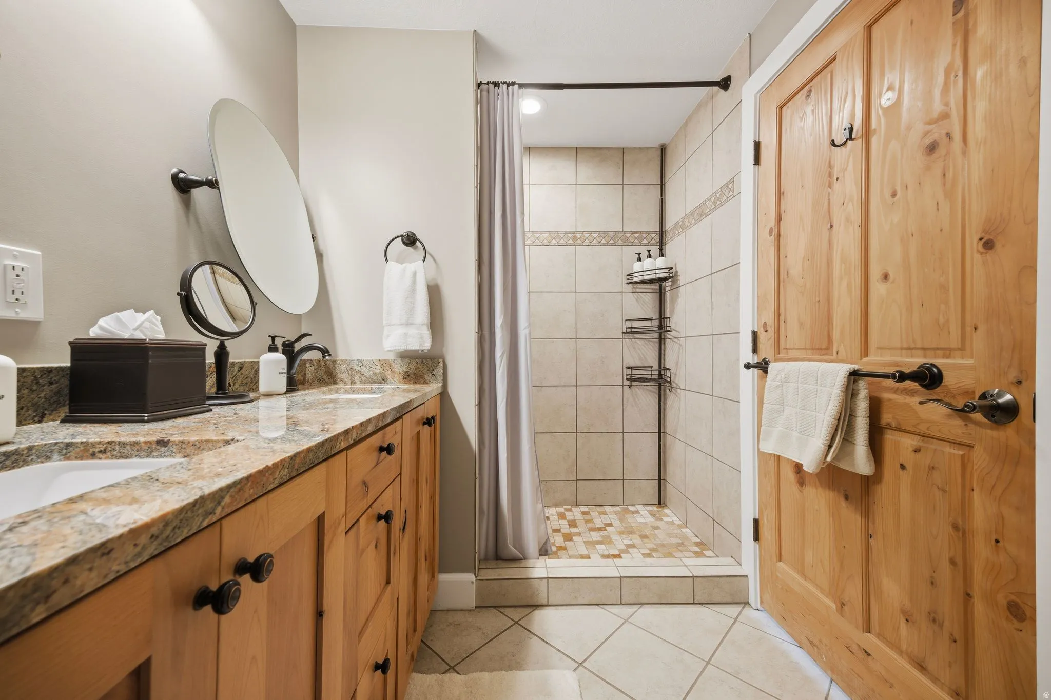 Bathroom with a stall shower, double vanity, and light tile patterned floors