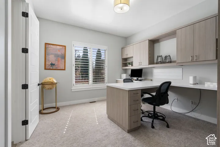 Office space featuring light colored carpet and built in study area