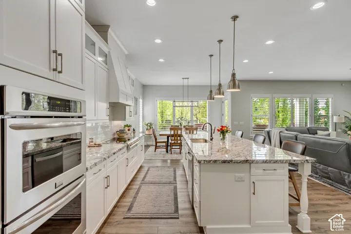 Kitchen featuring white cabinetry, a breakfast bar area, stainless steel appliances, light stone countertops, and open floor plan