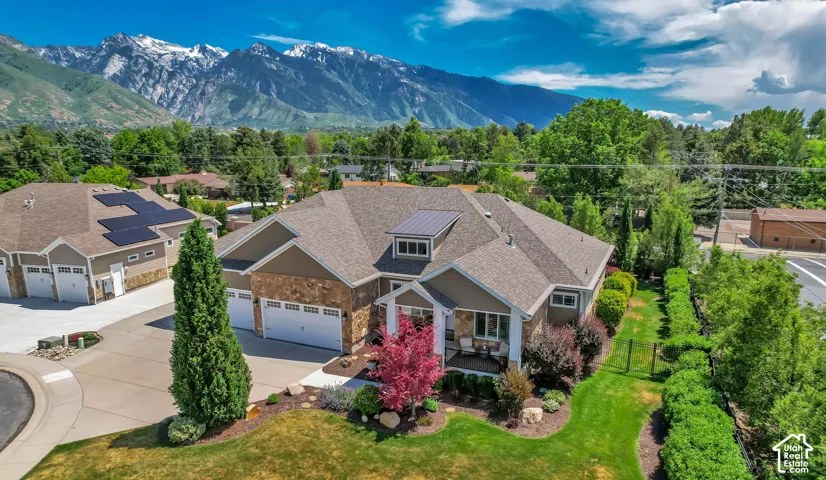 Contemporary residence featuring a multi-car garage, stone and siding exterior, dormer windows, and mature landscaping