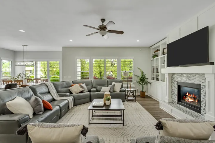 Living area with wood finished floors, a fireplace, a ceiling fan, recessed lighting, and built in shelves