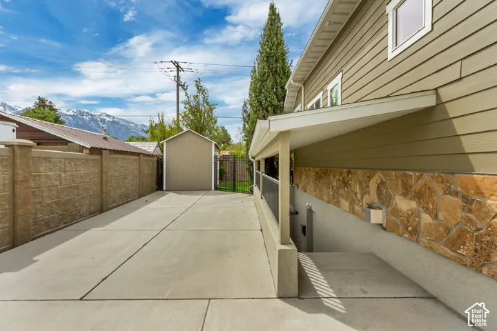 View of side of home featuring stone siding and a storage unit
