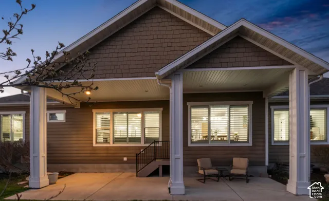 Back of property at dusk featuring a patio