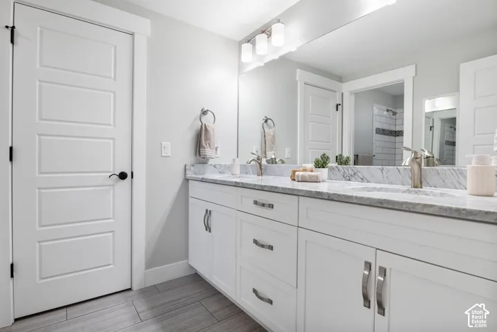 Full bath featuring double vanity and a tile shower