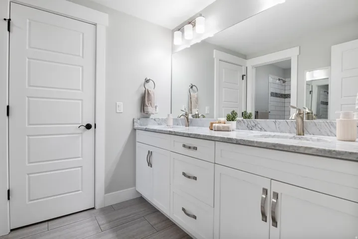 Full bath featuring double vanity and a tile shower