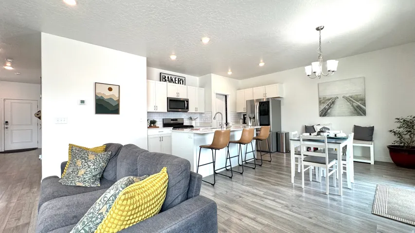 Open concept living space featuring wood-finish flooring, recessed lighting, and a modern kitchen with white cabinetry and stainless steel appliances