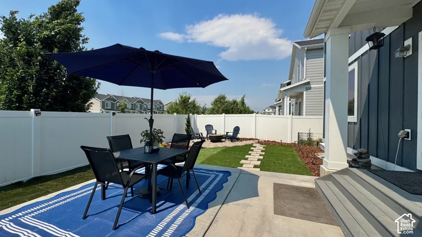 Expansive backyard featuring a white vinyl privacy fence, concrete patio, and segmented stone walkway