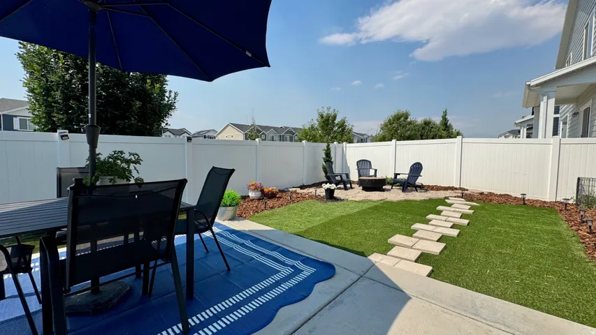 Patio with concrete slab, artificial turf lawn, and a stone stepping path