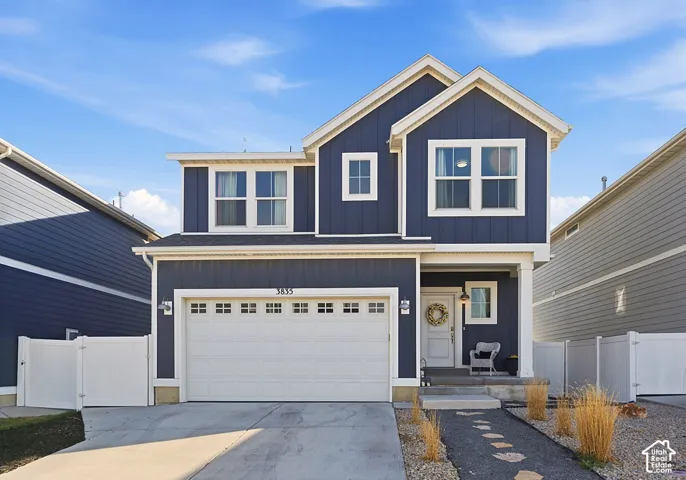 Two-story residence featuring blue vertical board-and-batten siding, a gabled roofline, a two-car garage, and a covered front entryway with white structural columns