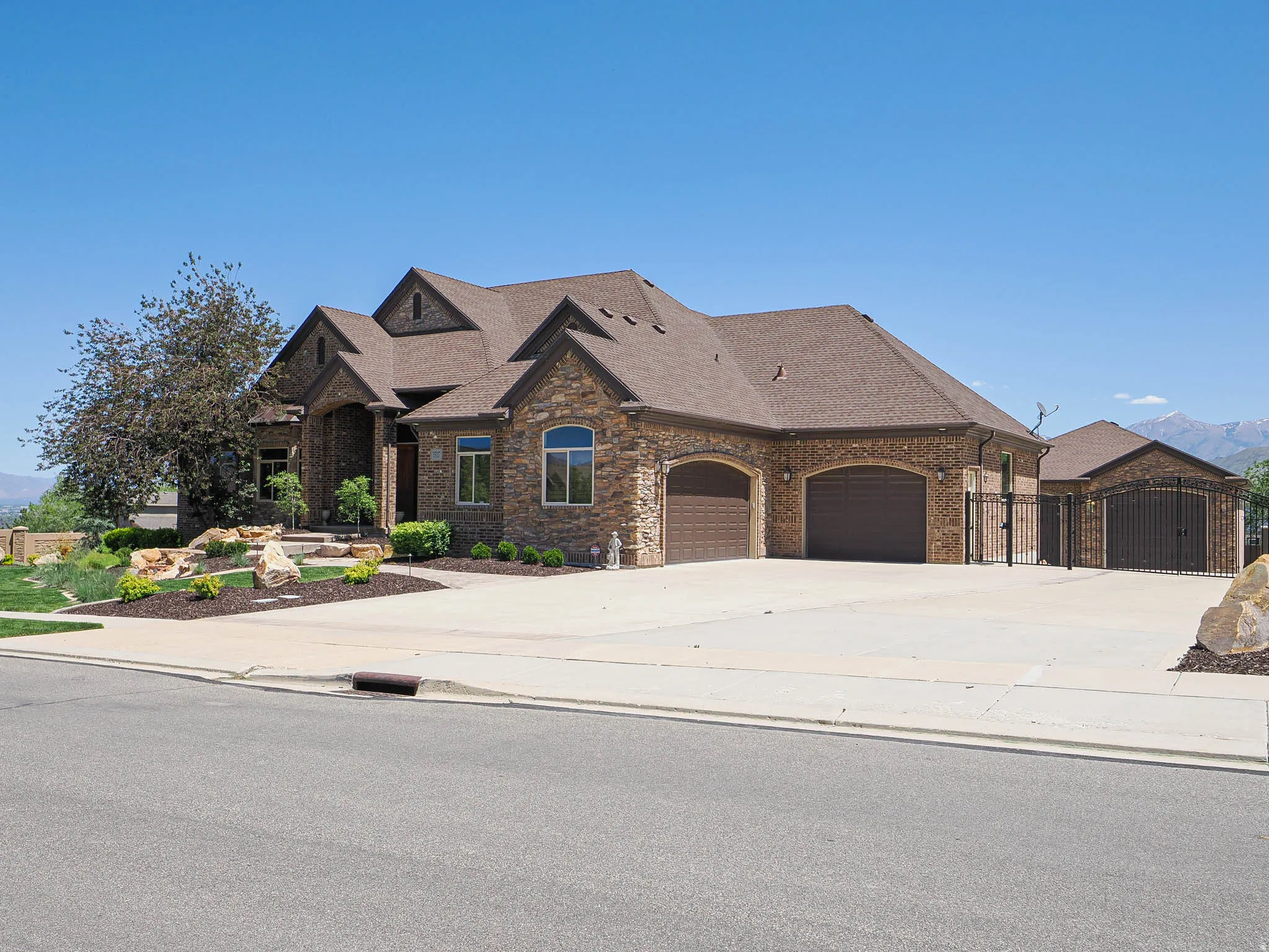Stone and brick veneer exterior featuring multiple gables and a multi-car driveway