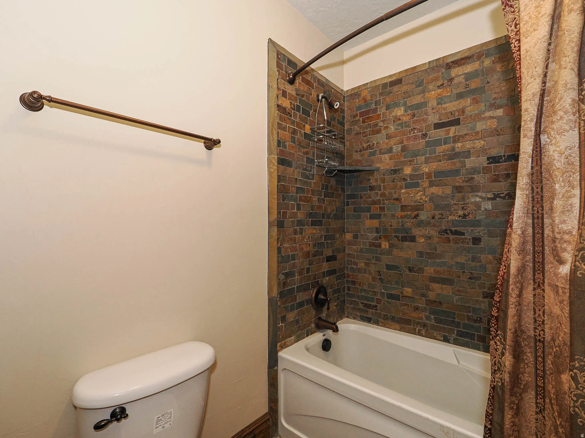 Bathroom featuring a tub/shower combination with a multi-toned brick-style tile surround