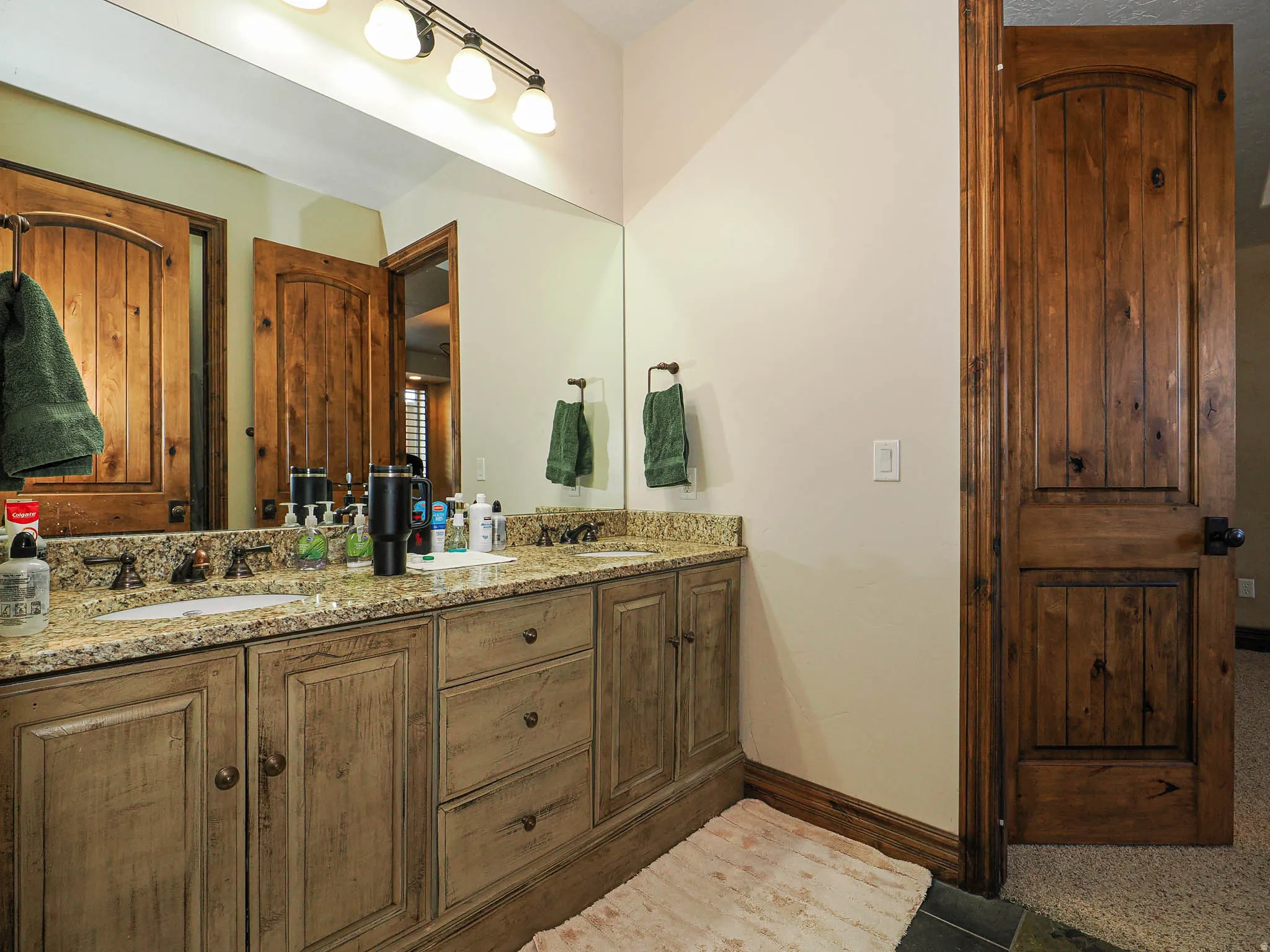 Bathroom vanity featuring dual under-mount sinks set in a granite-finish countertop