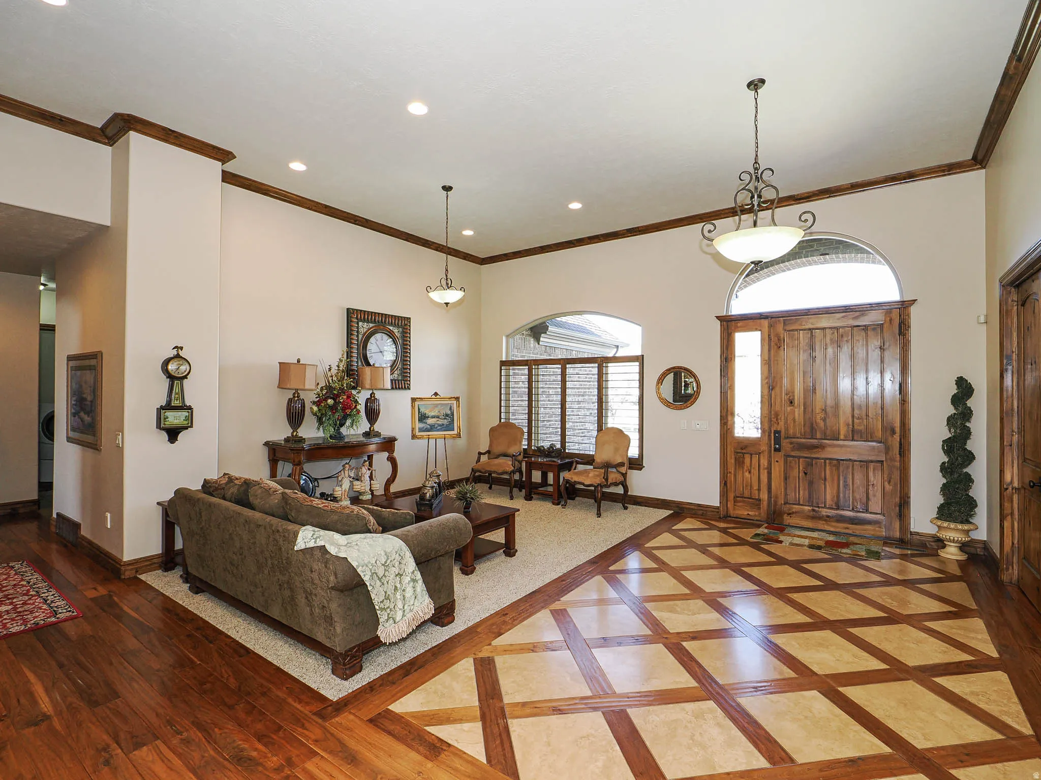 Expansive entry featuring a wood-finish door with an arched transom, patterned tile flooring with wood-finish accents, recessed lighting, and crown molding