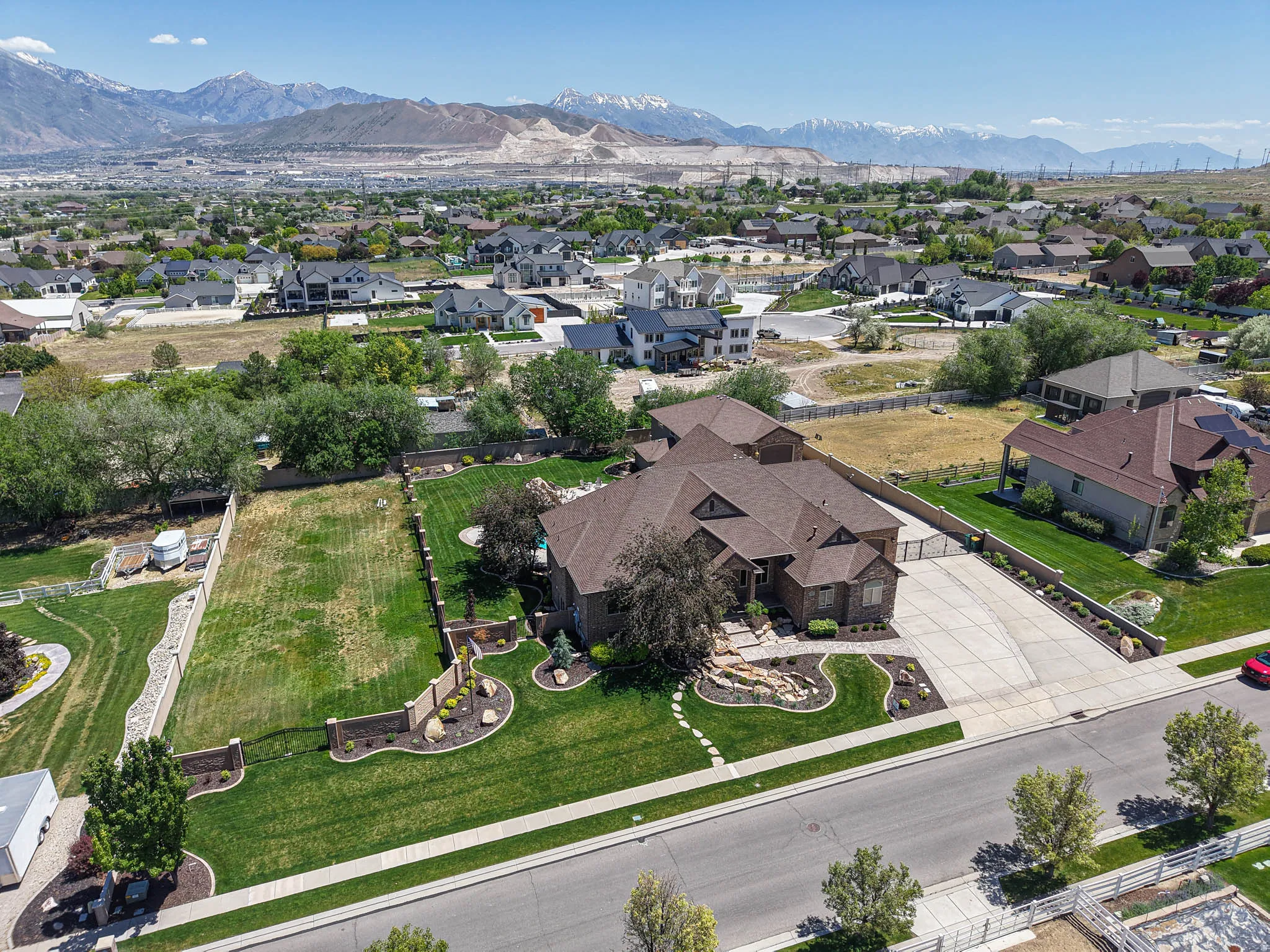 Spacious property featuring a large residence with a multi-gabled roof, extensive concrete driveway, and manicured front landscaping