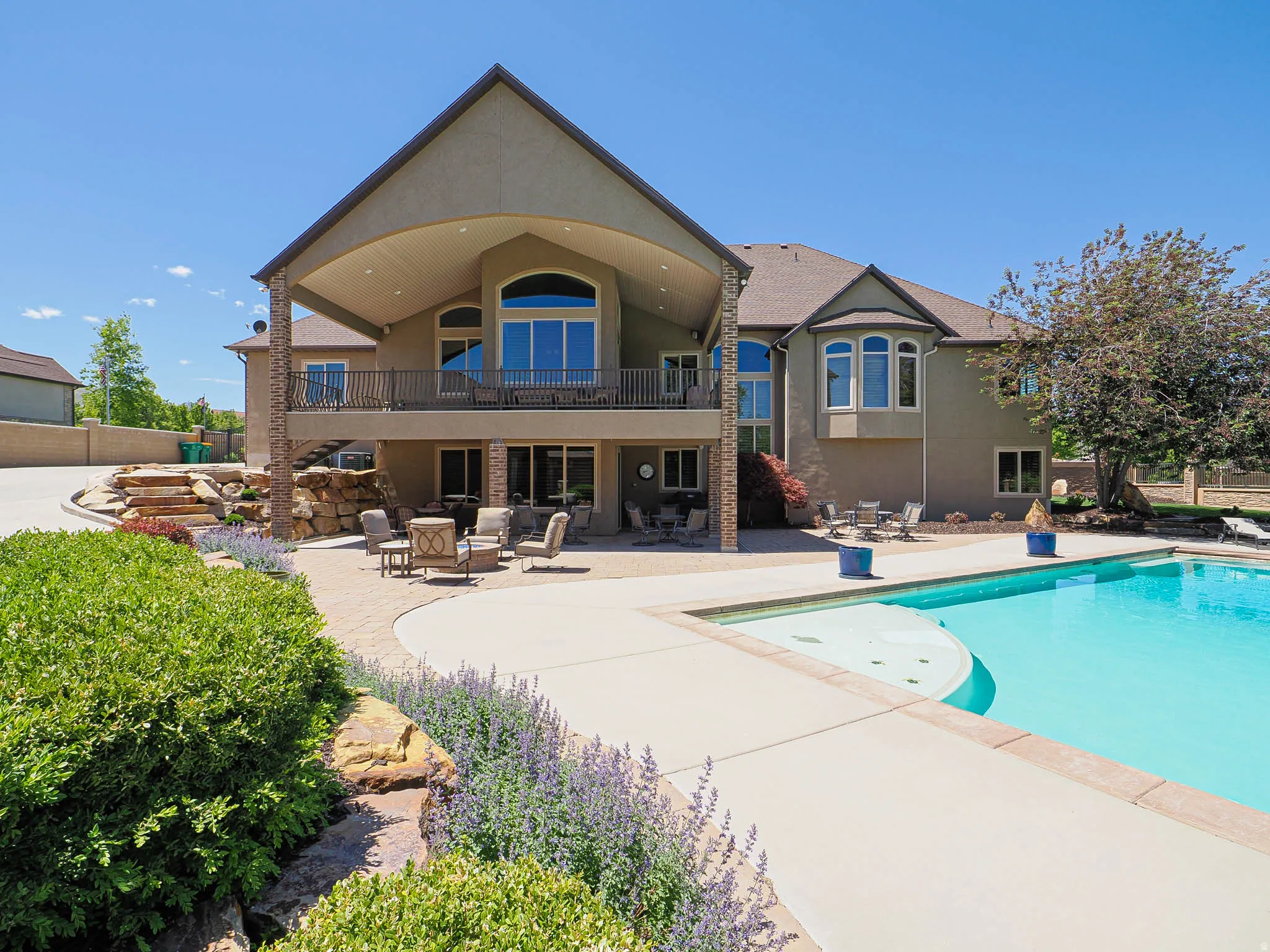 Expansive exterior featuring a large in-ground swimming pool, a spacious patio area, and a covered balcony