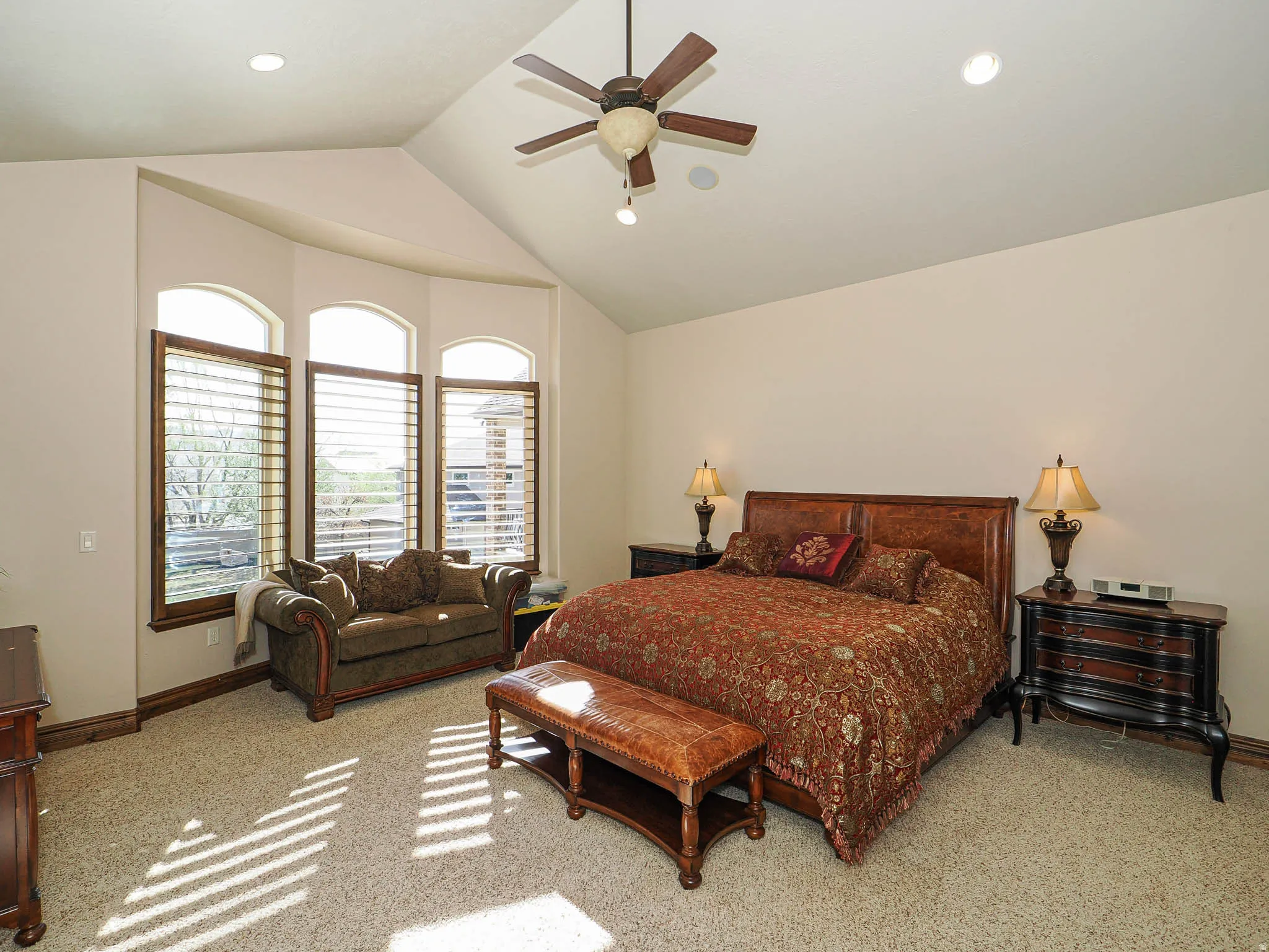 Vaulted ceiling with a ceiling fan, recessed lighting, and bay windows featuring plantation shutters