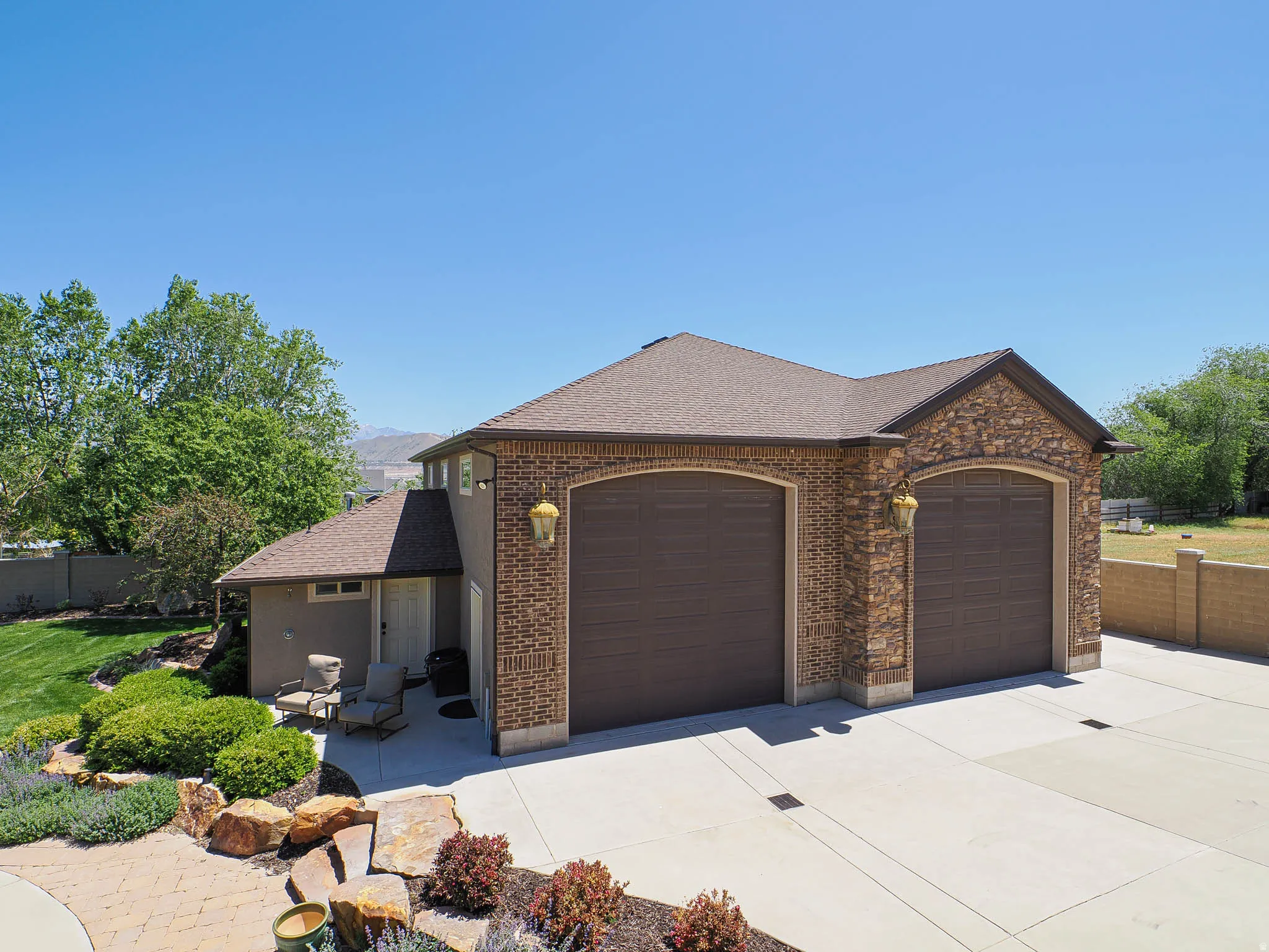 Two-car garage with arched doors, brick and stone facade, and sconce lighting