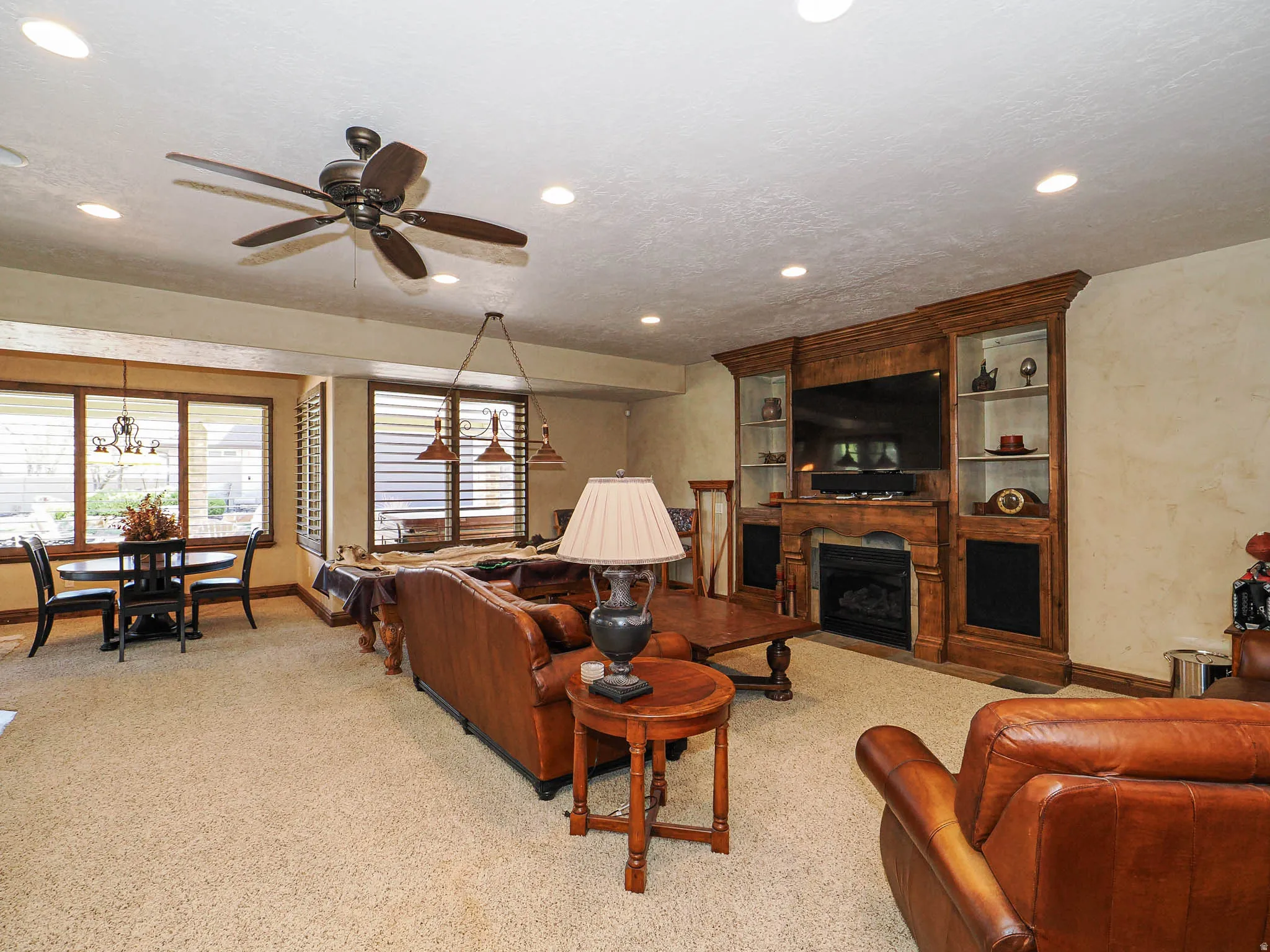Living area featuring a built-in entertainment center with integrated fireplace, recessed lighting, ceiling fan, and carpet flooring