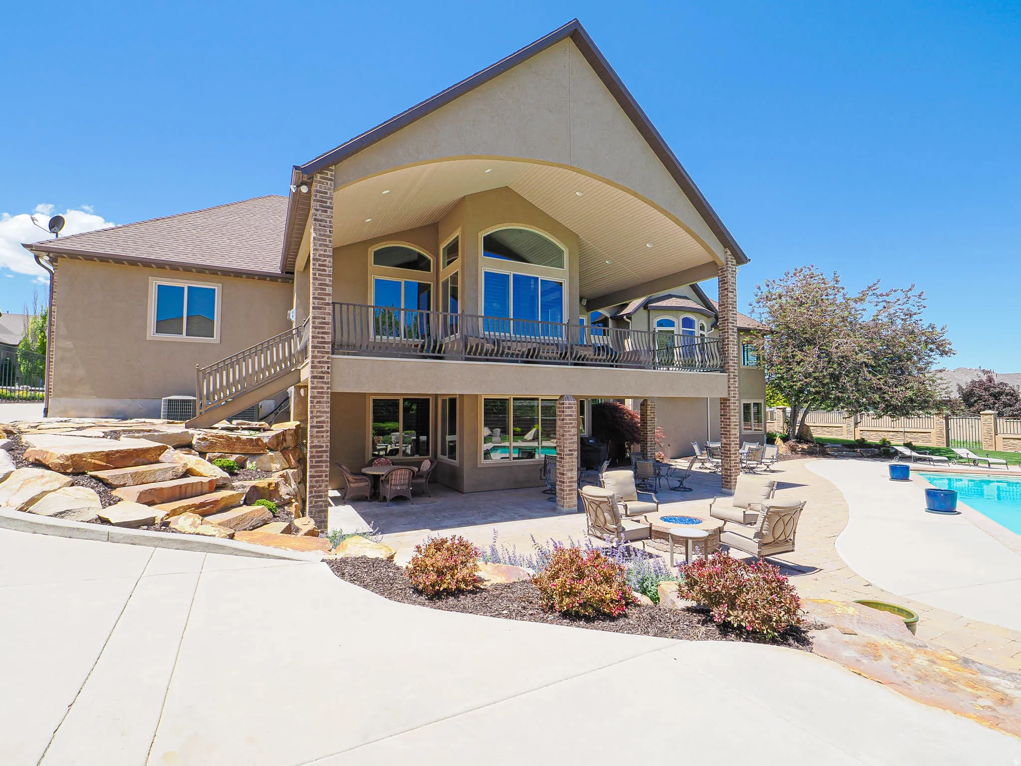 Multi-level exterior featuring a covered patio, upper-level balcony with a railing, and an in-ground swimming pool