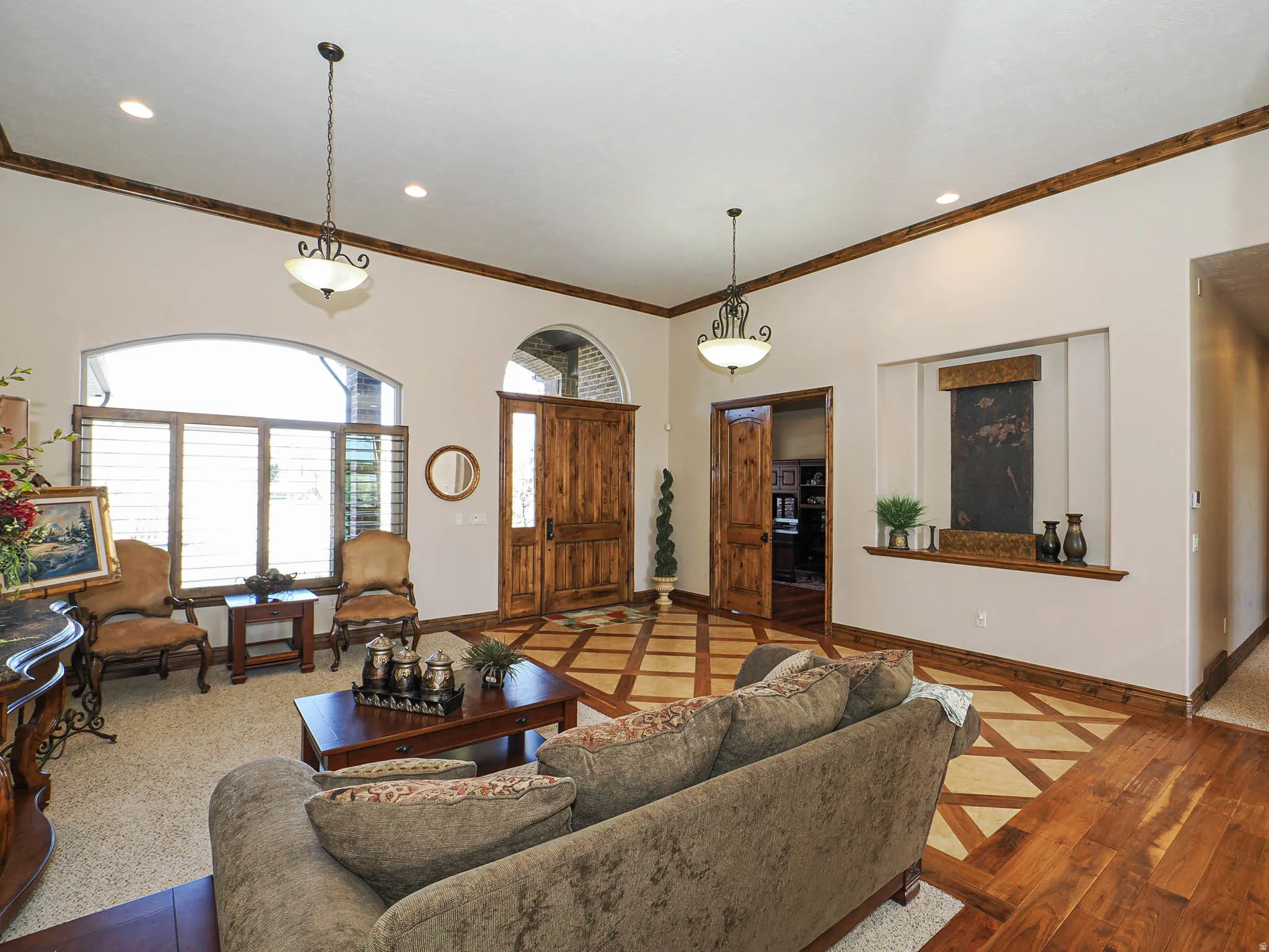 Spacious living area featuring intricate wood-finish flooring, a grand arched entryway, and a prominent recessed wall art niche