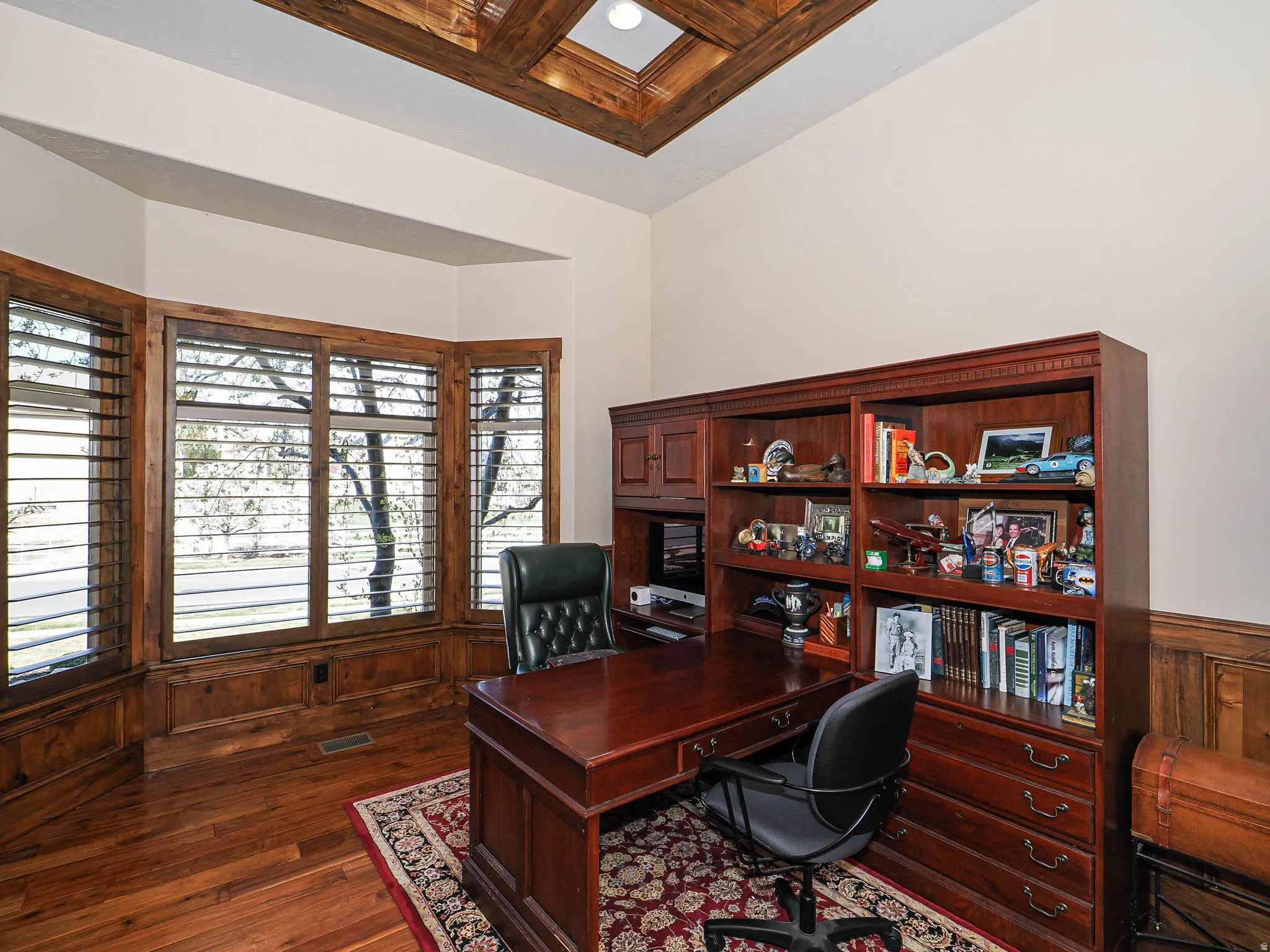 Room featuring wood-finish flooring, a tray ceiling with wood beam accents, and extensive built-in cabinetry