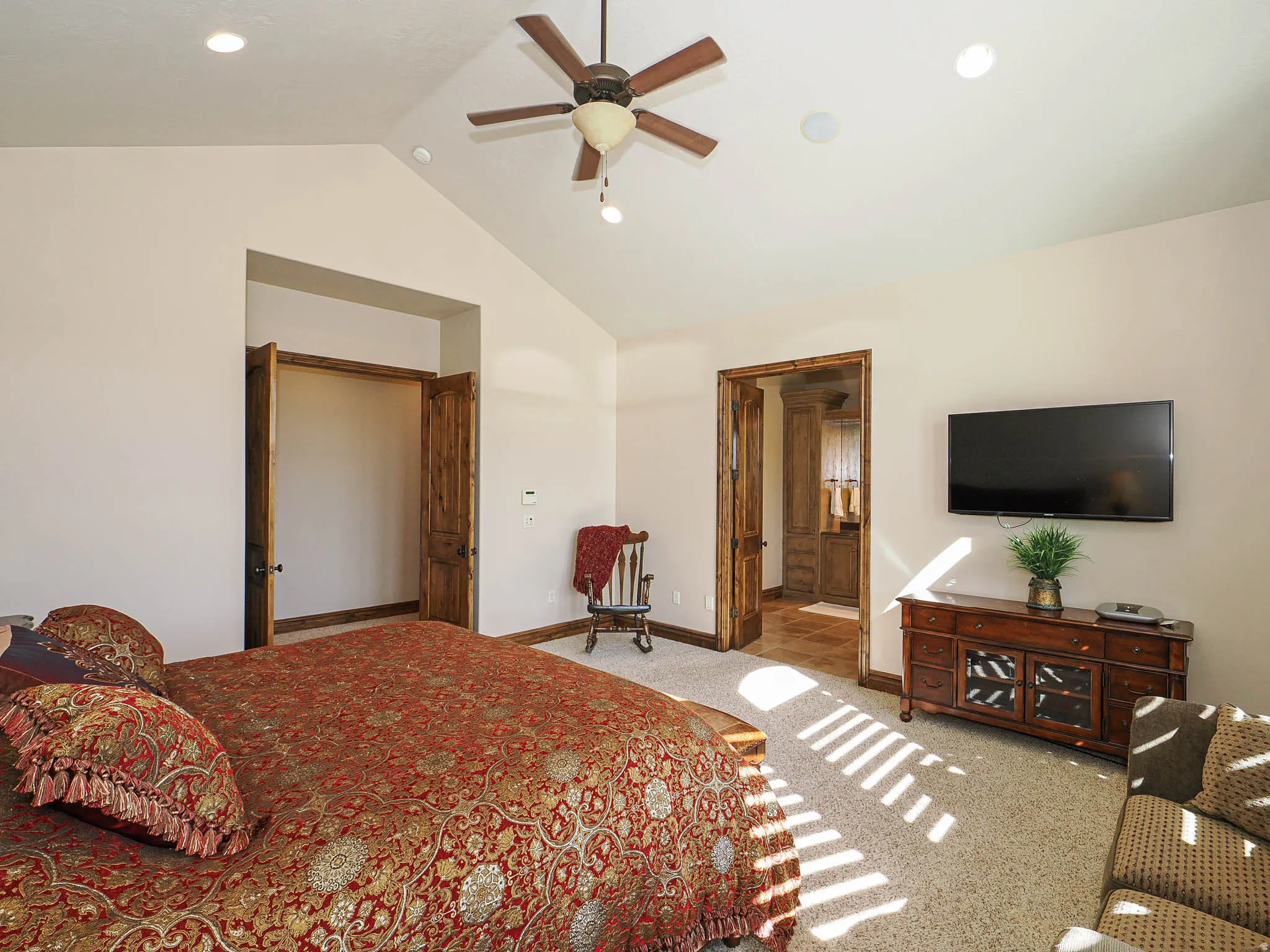 Vaulted ceiling room featuring a ceiling fan, recessed lighting, and rich wood-finish doors