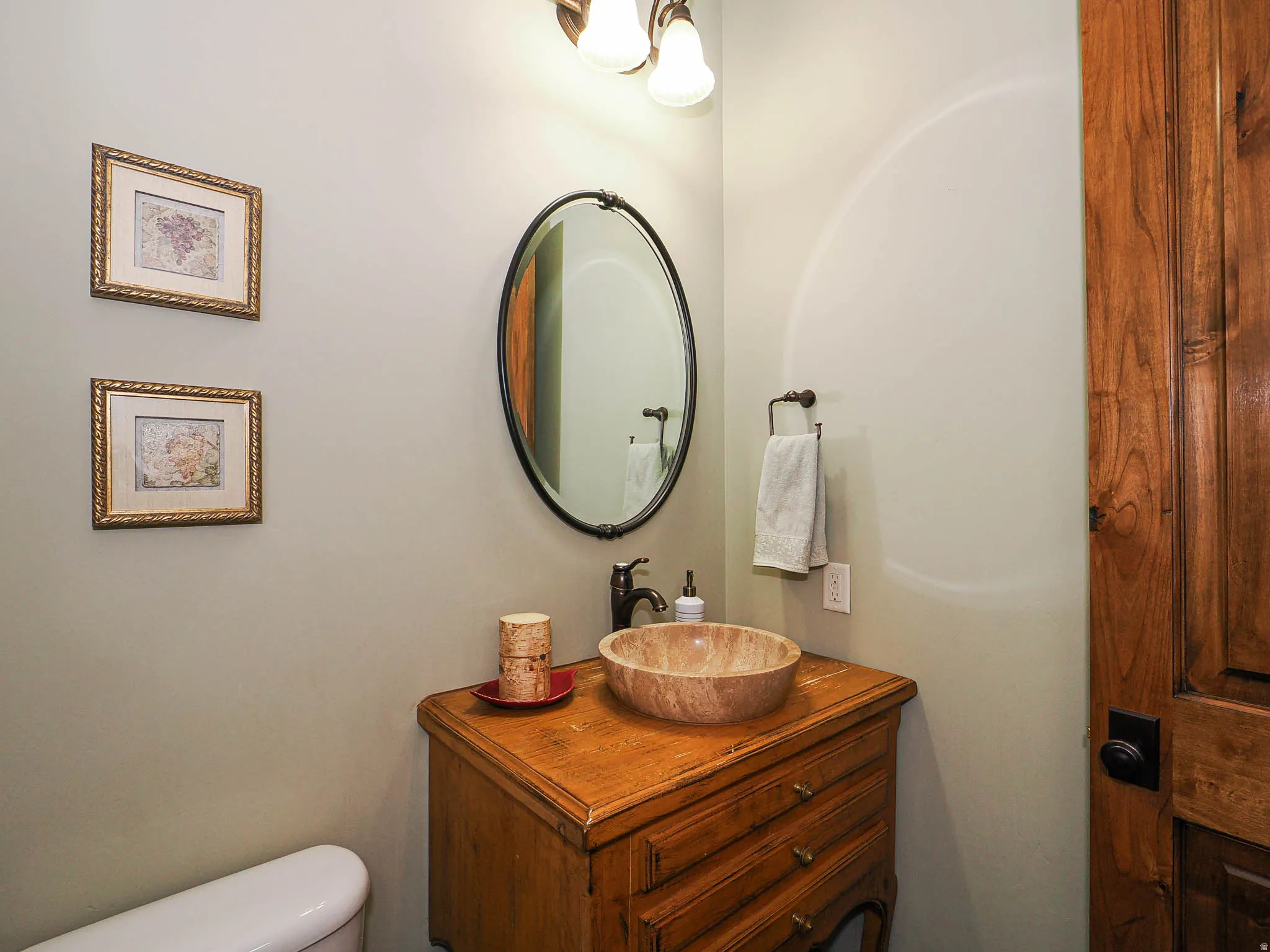 Wood vanity with a natural stone vessel sink and oil-rubbed bronze faucet