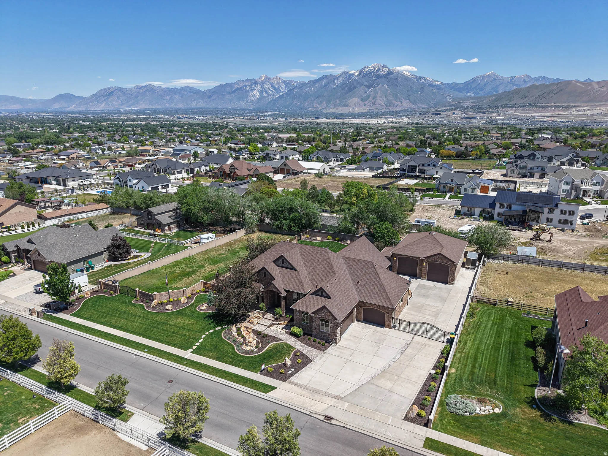Expansive property featuring a multi-gabled roofline, stone and brick facade, a three-car garage, and a gated driveway