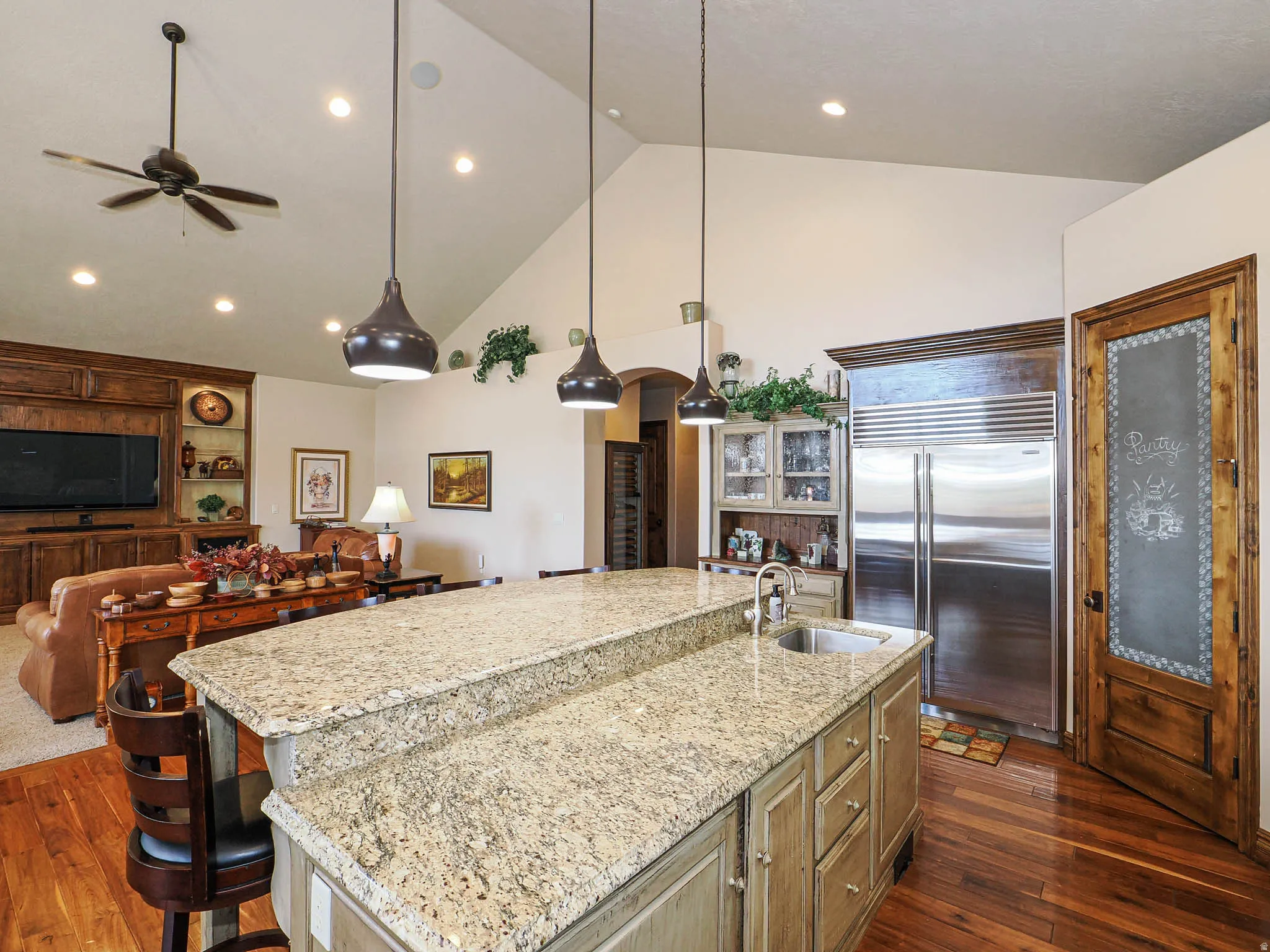 Spacious kitchen island with granite countertop and integrated sink, complemented by warm wood-finish flooring