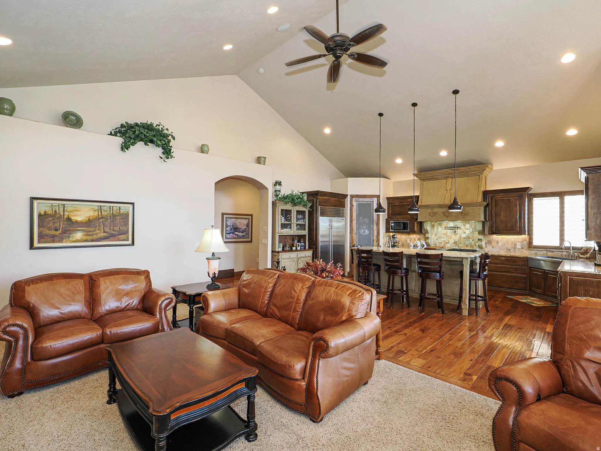 Open-concept living area featuring a vaulted ceiling with recessed lighting and a ceiling fan