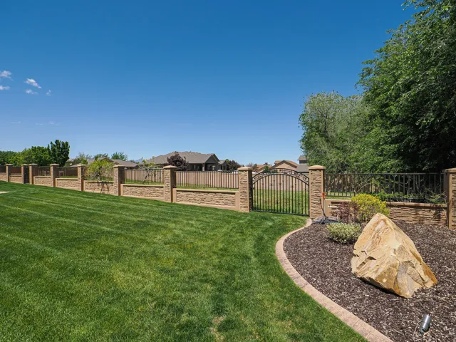 Manicured lawn with a decorative stone and wrought iron fence
