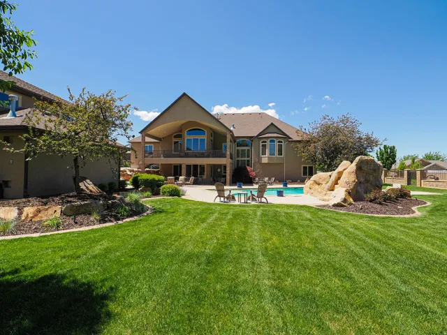 Expansive backyard featuring a large lawn, a swimming pool, and natural rock landscaping