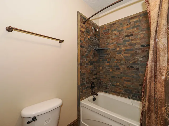 Bathroom featuring a tub/shower combination with a multi-toned brick-style tile surround